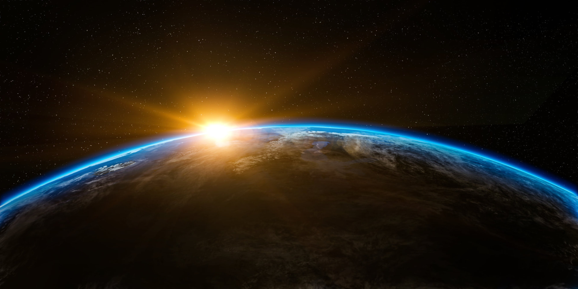 The sun rising over the curved horizon of the Earth, seen from space, with a thin blue atmosphere against a star-filled sky